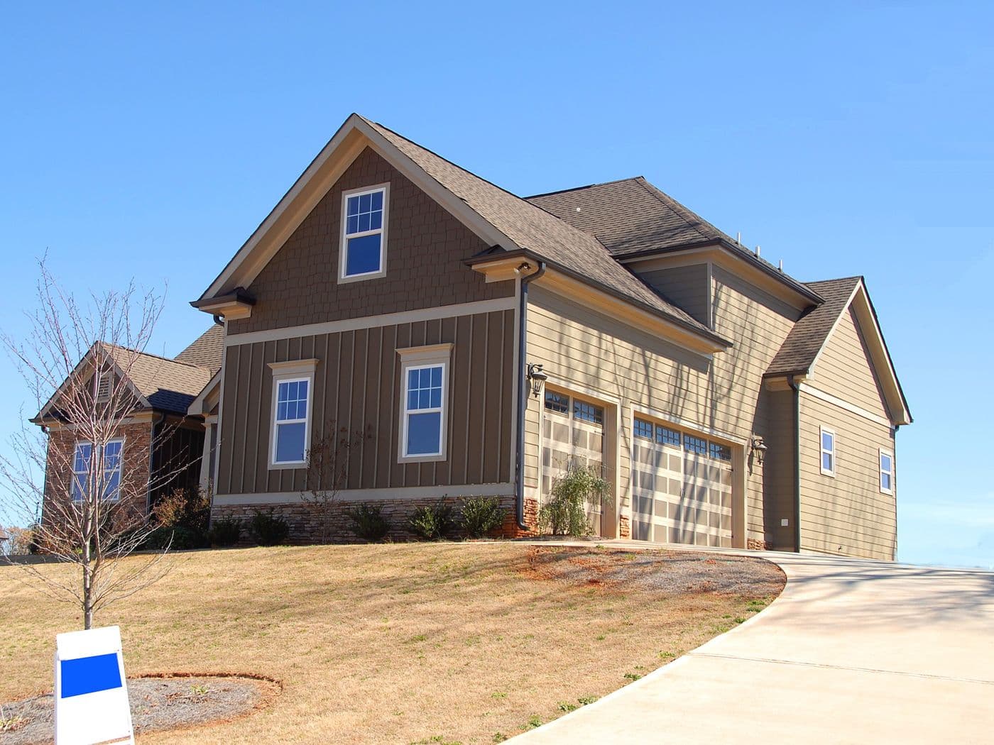 Brown two-story home with a for-sale sign